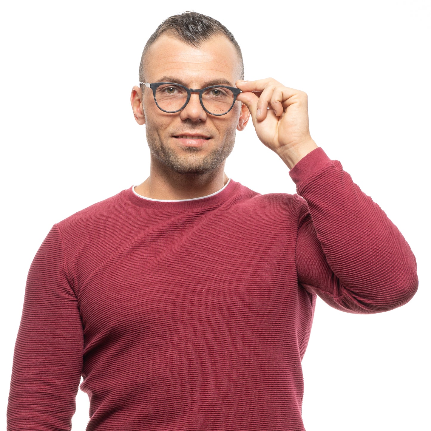 Man wearing glasses with a red sweater adjusting frames, standing against a white background.