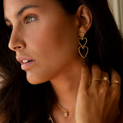 Woman wearing 24KAE JEWELS JEWELRY Mod. 12472Y/52 heart earrings, gold necklace, and rings.