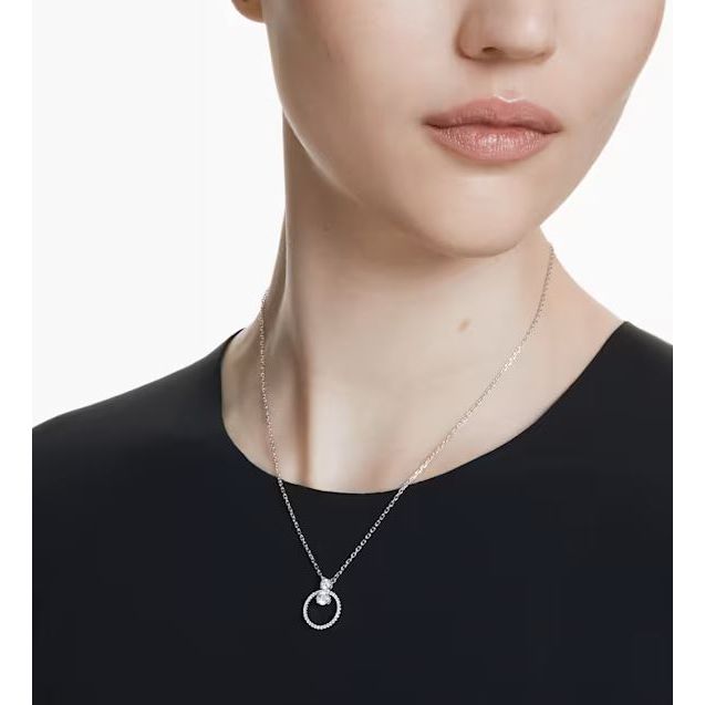 Woman wearing elegant silver necklace with circular pendant on a black dress