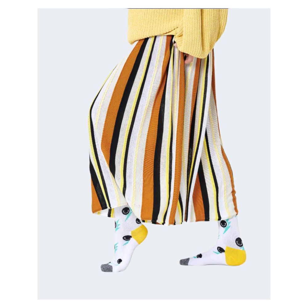 Woman wearing Happy Socks White Cotton Socks with smiley design, styled with a colorful striped skirt for a vibrant look.
