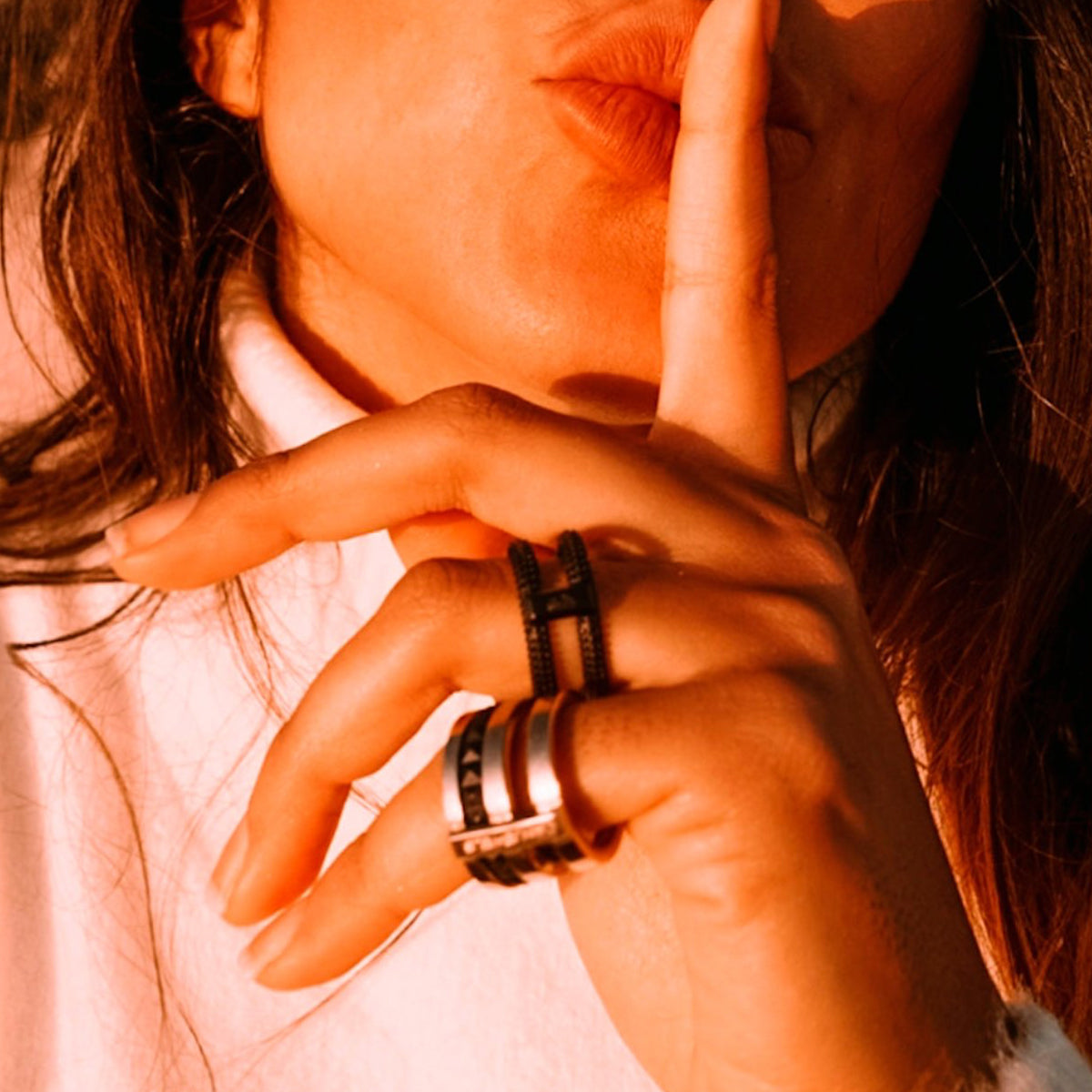 Woman wearing rings from AN JEWELS JEWELRY Mod. AR.R2NS02BK-9 collection, hand gesture with index finger on lips.