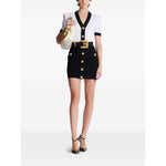 Model wearing Balmain Two-tone twisted knit bodycon dress with gold buttons and V-neck, showcasing a stylish fashion ensemble.