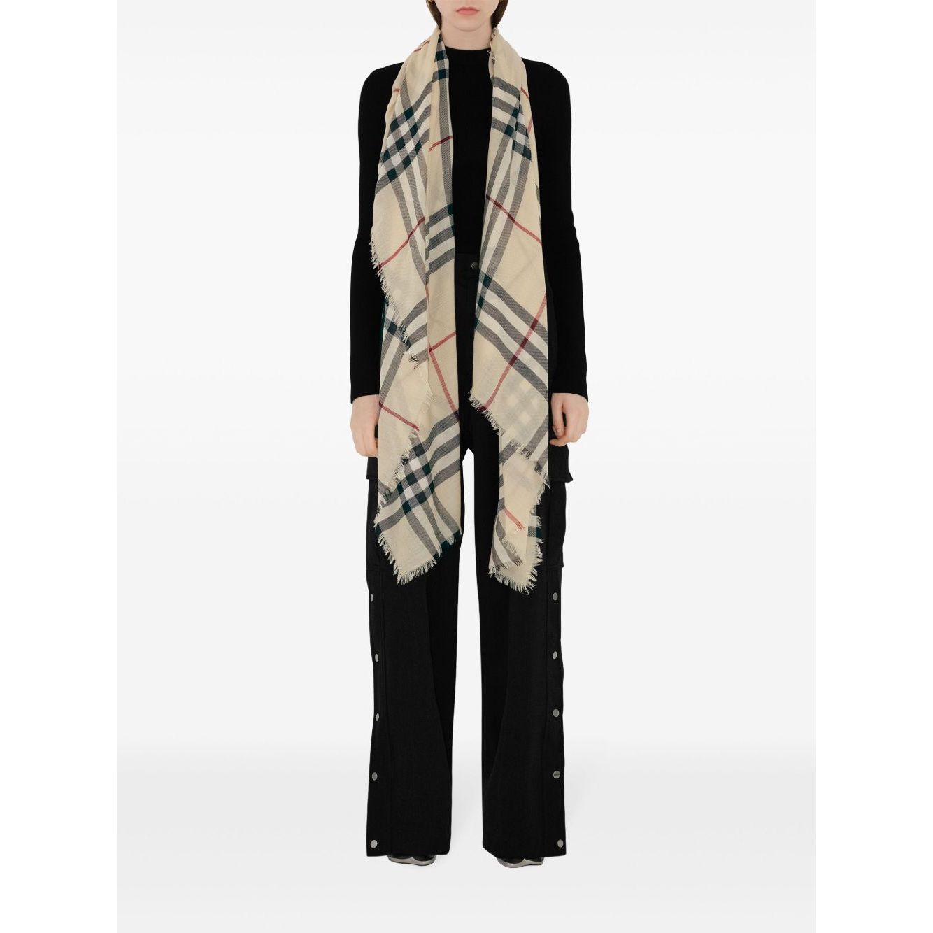 Model wearing a Burberry Check wool scarf with beige house pattern, raw-cut edges, and logo tag, showcasing long length and stylish design.