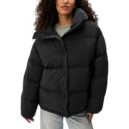 Woman wearing Calvin Klein Jeans Black Polyester Clothing, relaxed fit puffer jacket providing warmth and style with high collar design.