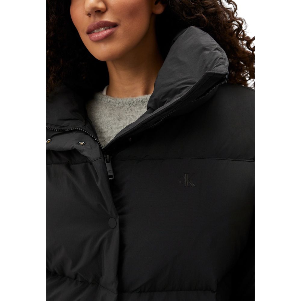 Woman wearing Calvin Klein Jeans Black Polyester Clothing Relaxed Puffer jacket with high collar, showcasing modern design and comfort.