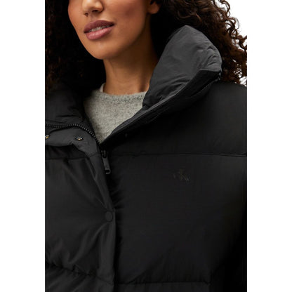 Woman wearing Calvin Klein Jeans Black Polyester Clothing Relaxed Puffer jacket with high collar, showcasing modern design and comfort.
