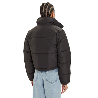 Rear view of Calvin Klein Jeans Black Polyester Coat, cropped puffer jacket with high collar, worn by model with braided hair, in jeans.