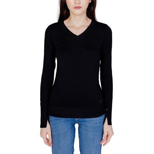 Woman wearing Guess Black Cotton Sweatshirt with V-neck and buttoned sleeves, paired with blue jeans, showcasing elegant and casual style.