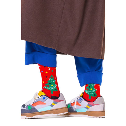 Happy Socks Red Cotton Socks with holiday design featuring Christmas trees and 'Happy Holidays' text, worn with colorful shoes and blue pants.