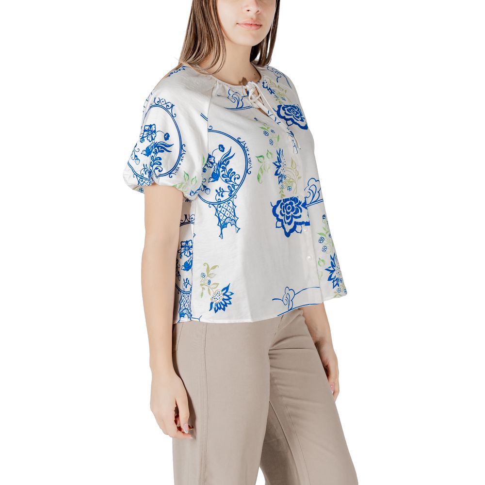 Woman wearing a stylish blue and white patterned top and beige pants.