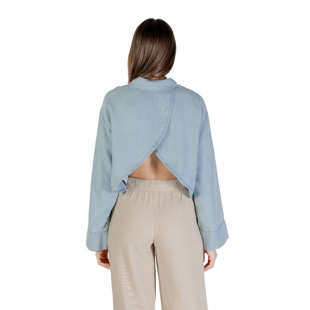 Back view of Only Light Blue Lyocell Blouse with long sleeves, paired with beige trousers.