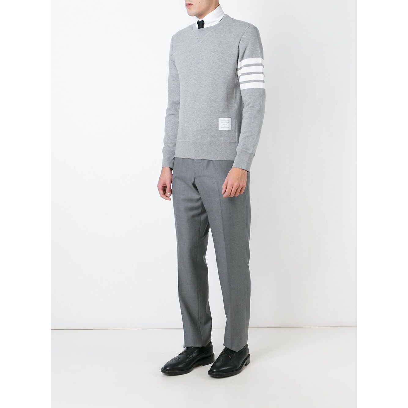 Model wearing Thom Browne Sweaters Grey with 4-Bar stripe, loopback cotton jersey, V insert neckline, and ribbed trims.