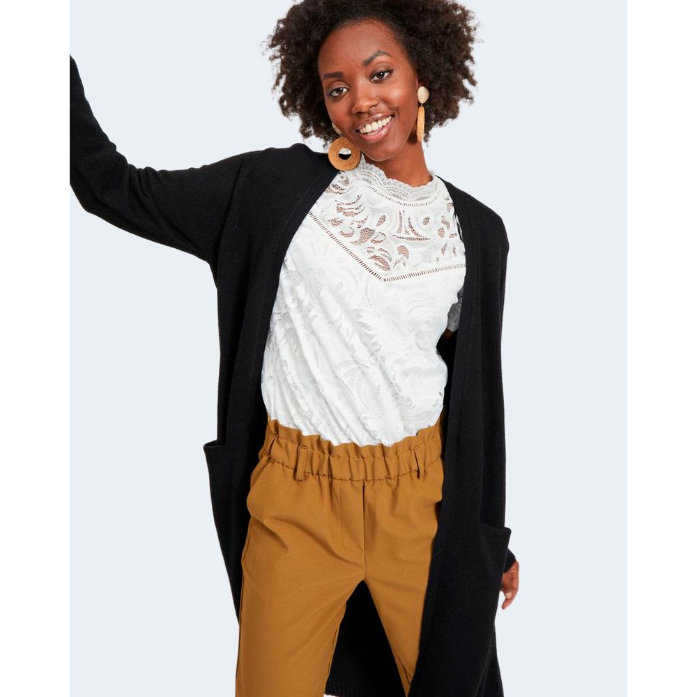 Woman wearing Vila Clothes Black Viscose Cardigan with long sleeves, white lace top, and mustard pants.