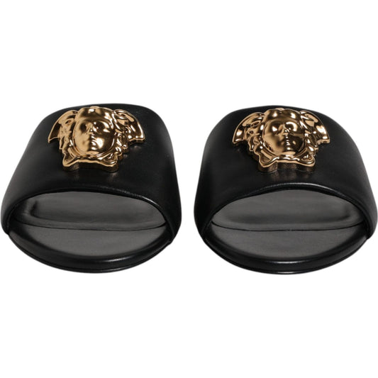 Versace black leather slip-on slides with gold logo plaque, open toe, high-quality, luxurious design, ideal for comfort, made in Italy.